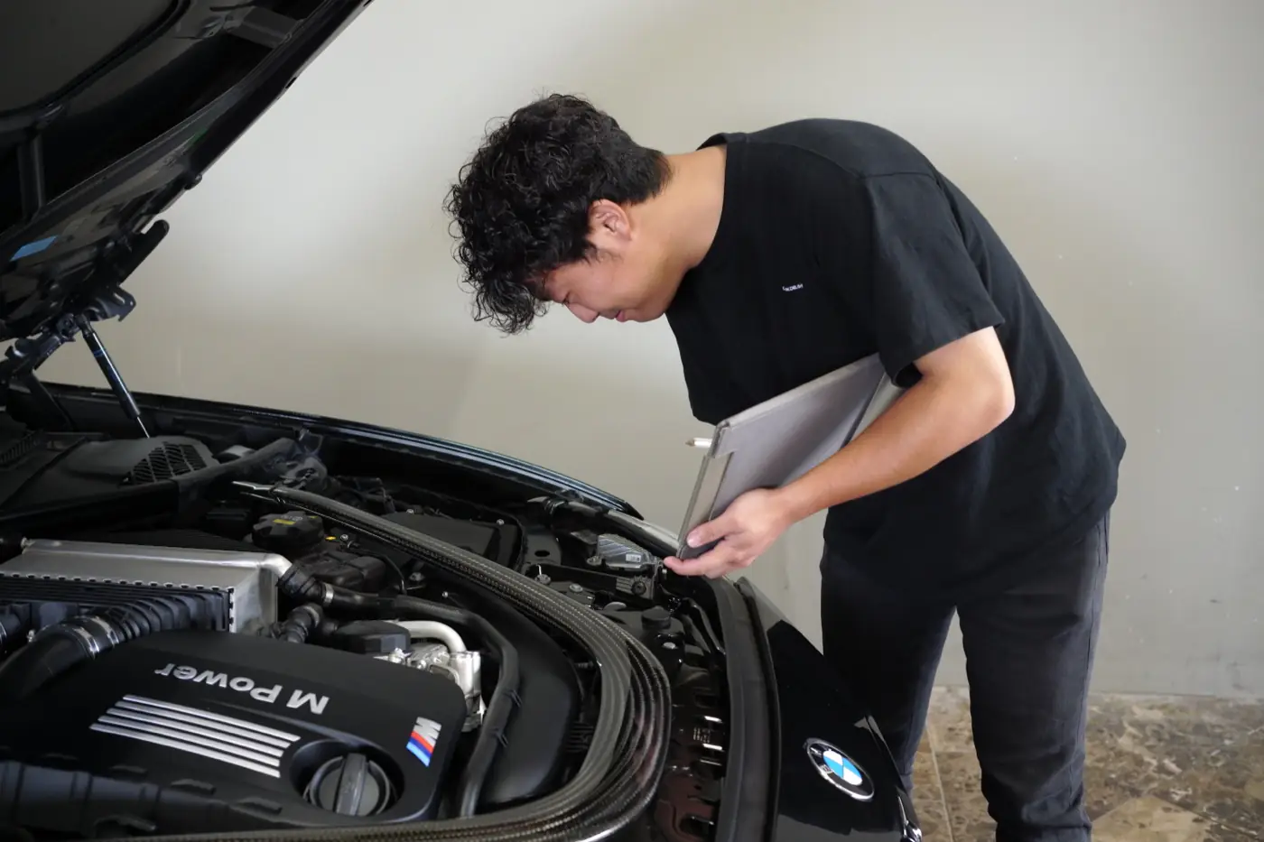 BMW Mのエンジンルームを確認するスタッフ（査定の様子）